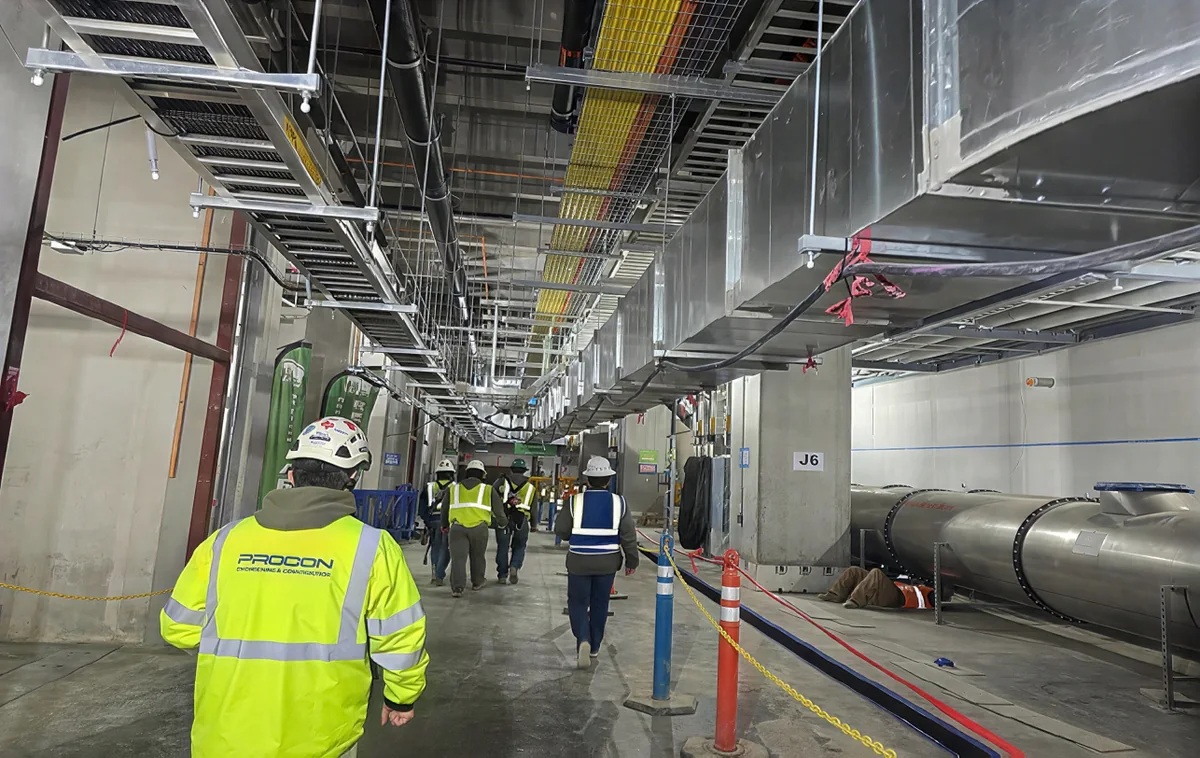 PROCON crew walking a utility corridor under cable trays and ductwork